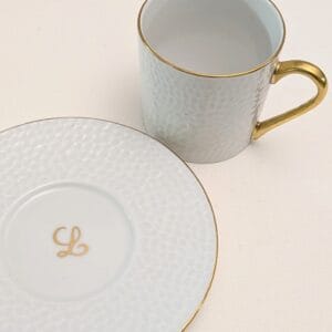 une tasse à café et une soucoupe blanches et dorées