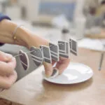 Aude Novikoff dans son atelier tenant les pièces en porcelaine peintes à la main