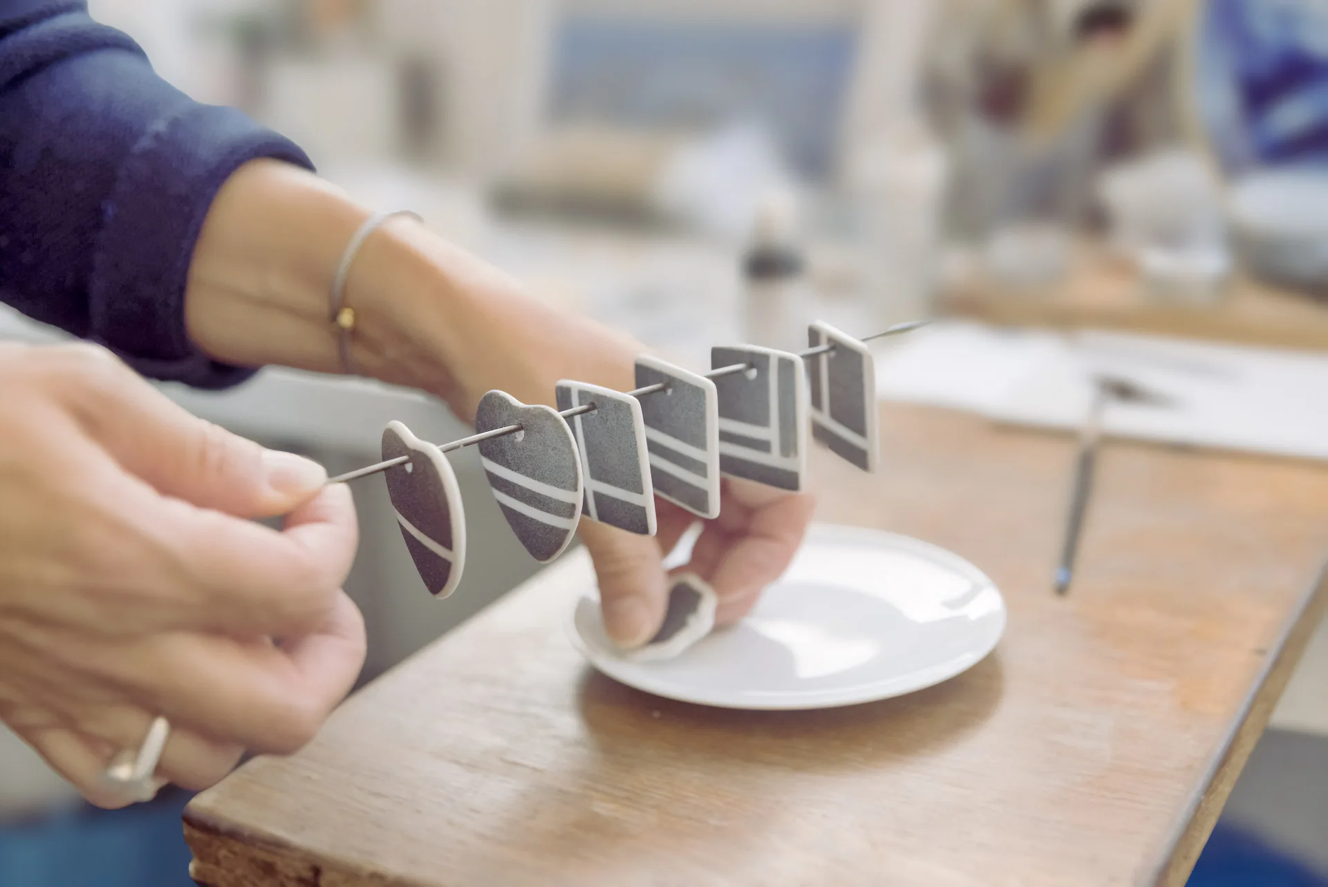 Aude Novikoff dans son atelier tenant les pièces en porcelaine peintes à la main