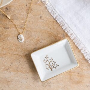 un vide-poche en porcelaine peinte à la main décoré avec un Arbre de vie à côté d'une serviette blanche